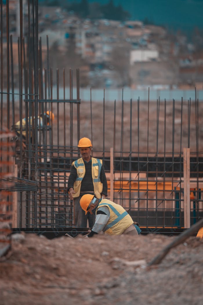 Construction workers on site adding steel reinforcement bars. Urban environment, teamwork in progress.
